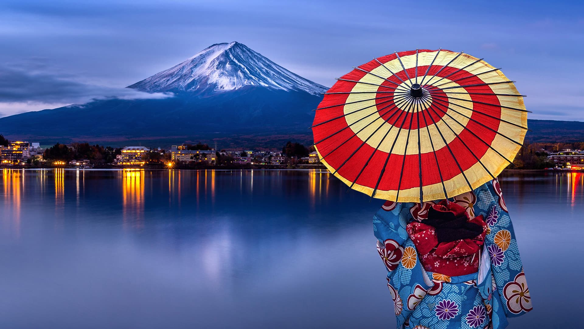 Người mặc kimono cầm ô giấy đứng bên hồ, núi Phú Sĩ phía xa lúc chạng vạng