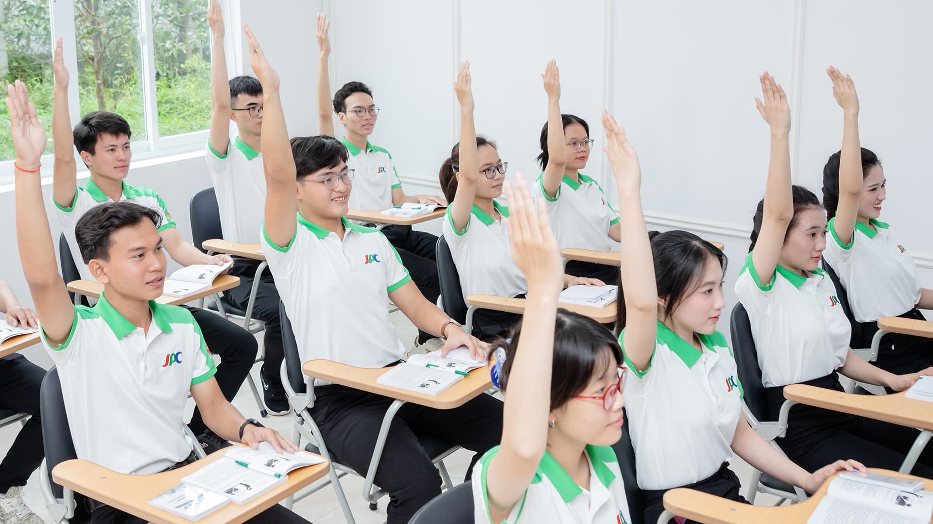Lớp học đông học viên mặc đồng phục Trường JPC cùng giơ tay phát biểu